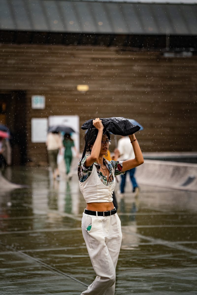 Pitti Uomo 104 - woman walking in rain with bag above head